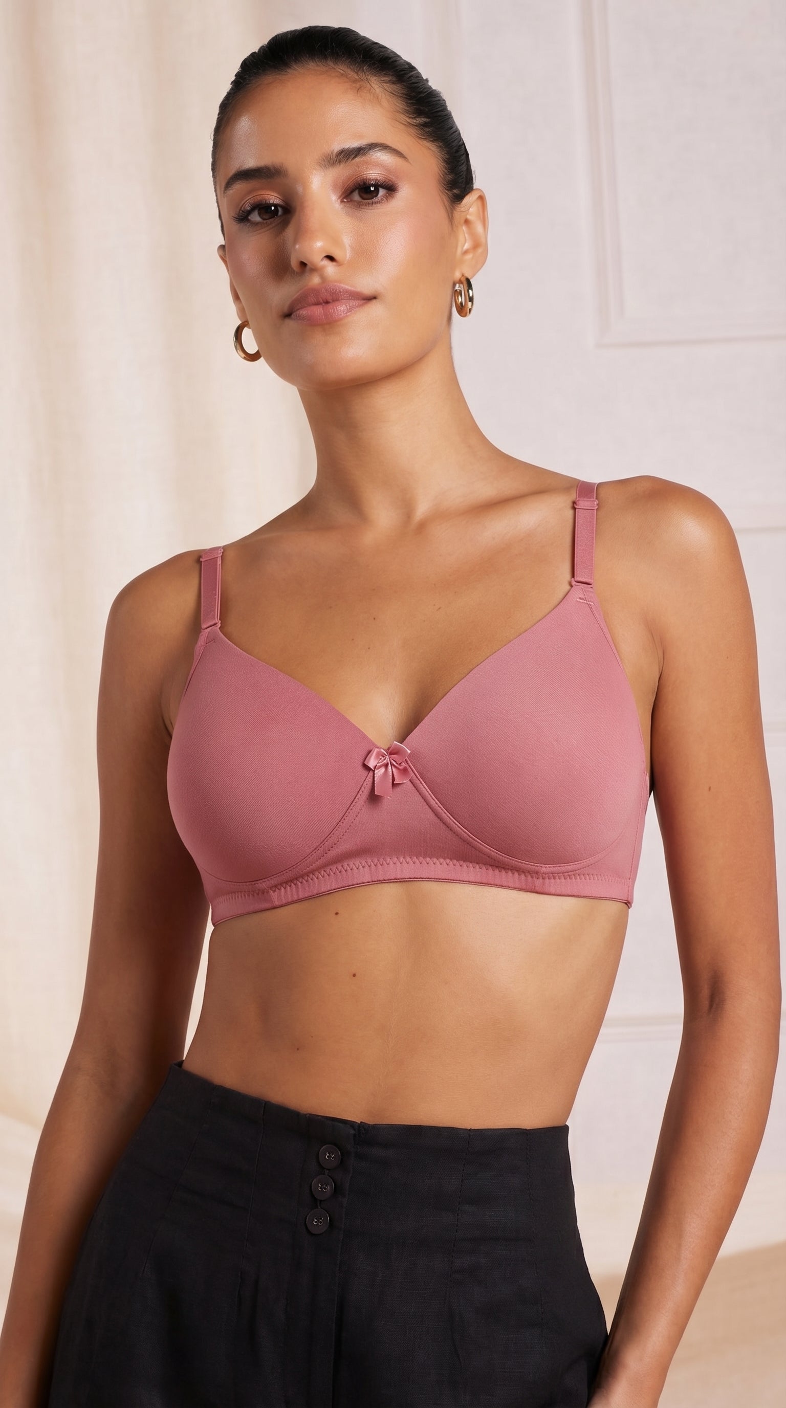 Woman wearing a pink bra against a plain background